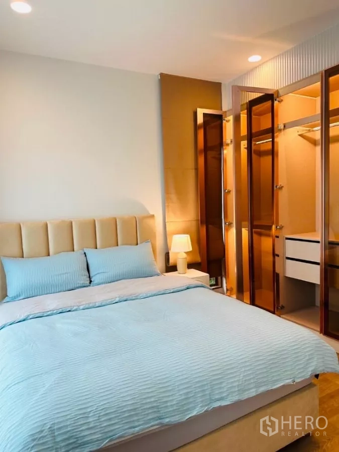 Detached House for rent or sale in Bang Kapi, Bangkok - Cozy bedroom with padded headboard next to a glass-door walk-in closet.