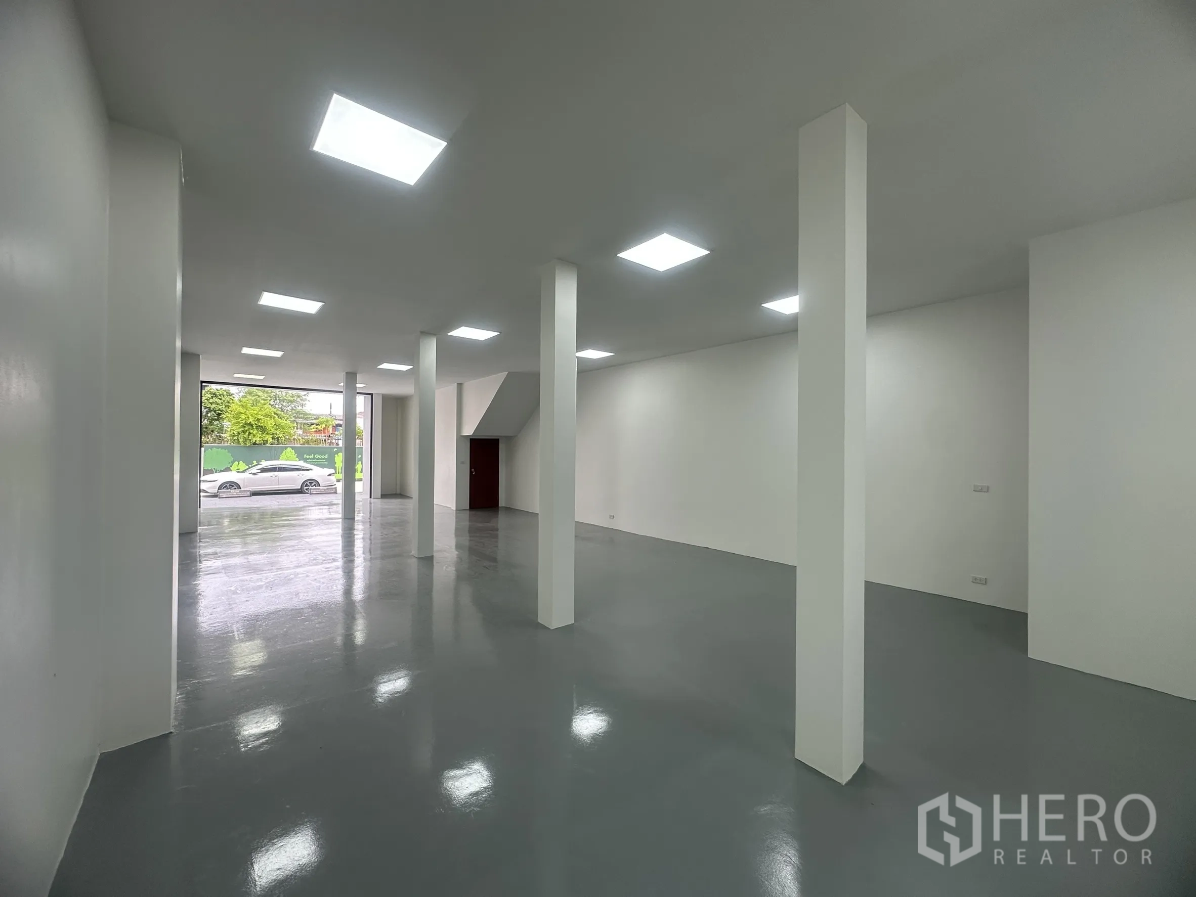 Warehouse for sale in Khlong Luang, Pathum Thani - Open-plan storage area with support columns and large roller door facing the street for easy loading.