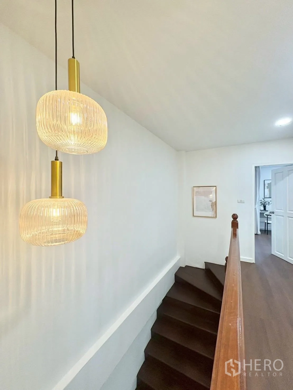 Townhouse for rent in Huai Khwang, Bangkok - Dark wood staircase with handrail illuminated by modern pendant lights.