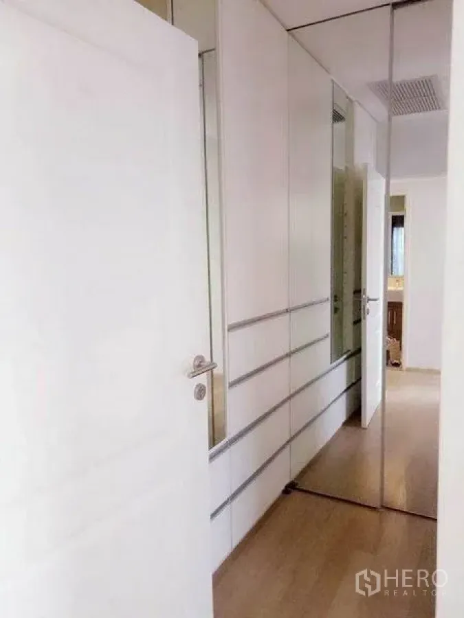 Condominium for rent in Bangkok - Bright hallway with built-in white wardrobes and mirrored doors in a Bangkok condo