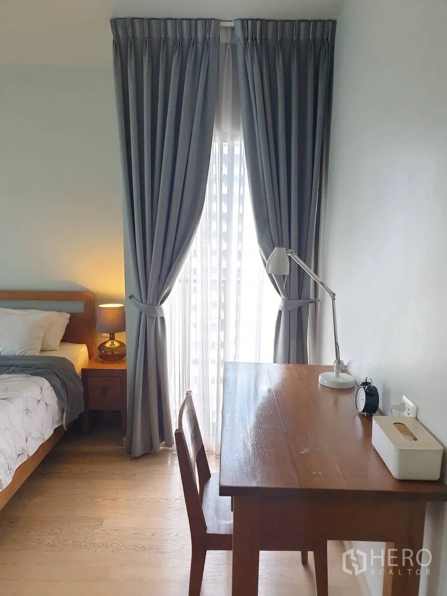 Condominium for rent or sale in Bangkok - Work desk and chair set next to a curtained window in the bedroom.