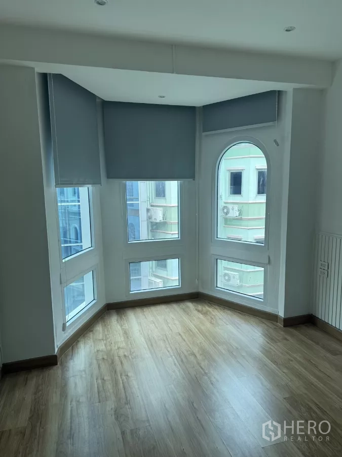 Shophouse for rent - Corner room featuring multiple floor-to-ceiling windows, arched pane, and wood-look flooring.