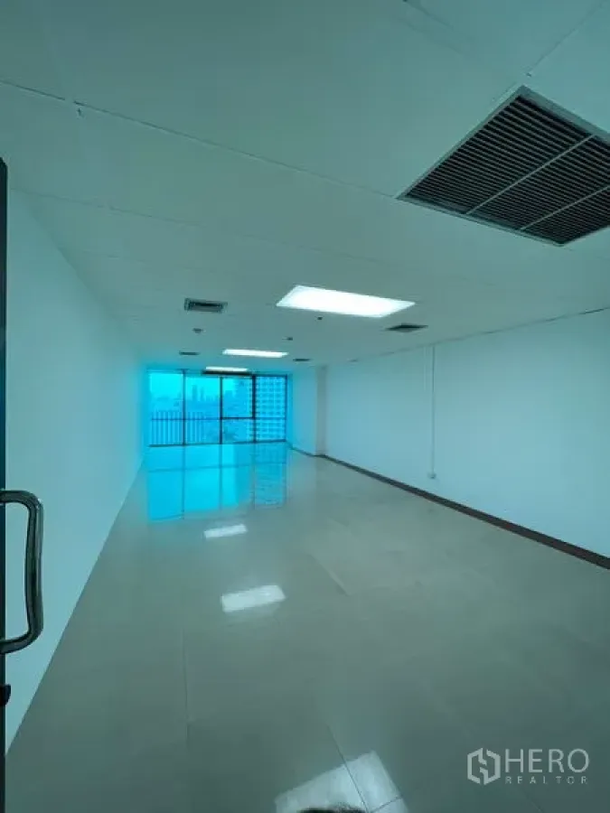 Office Space for rent in Huai Khwang, Bangkok - Long open‑plan office with glossy tiles, ceiling lights, air vents, and sliding glass doors to a balcony with city views near MRT Sutthisan.