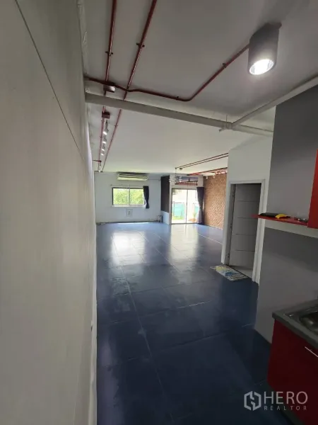 Office Space for rent in Watthana, Bangkok - Long view of flexible workspace with large window, track lighting, exposed piping, and a brick feature wall.