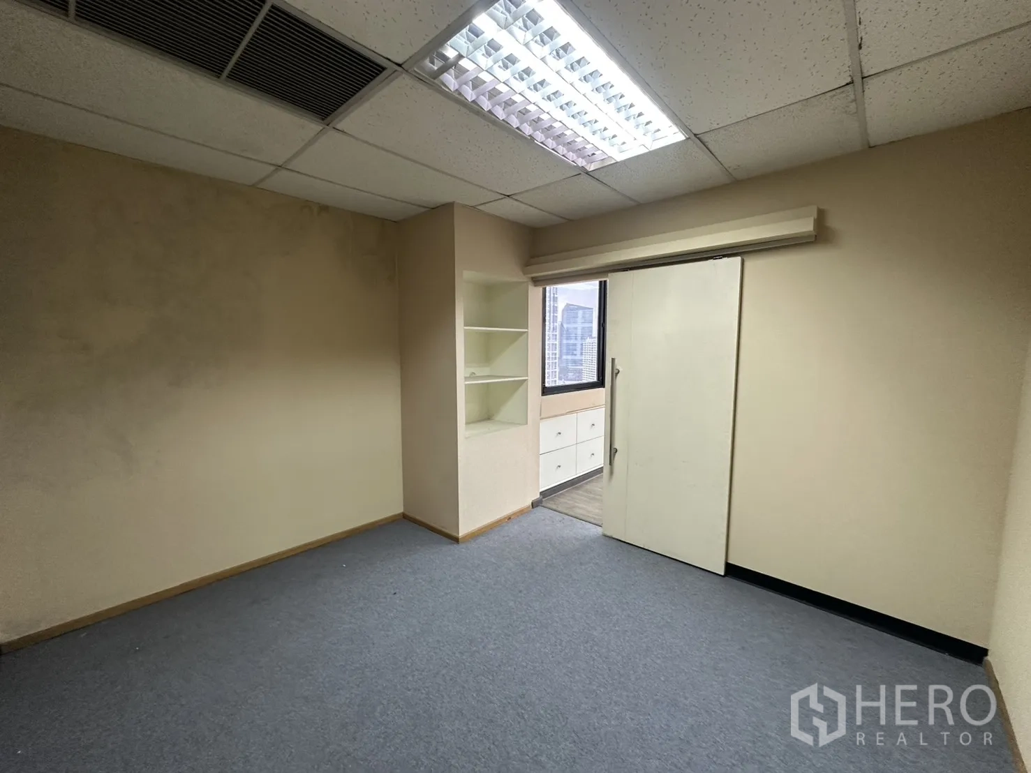 Office Space for rent in Bang Rak, Bangkok - Carpeted room with fluorescent lighting, a sliding door and an exterior window.