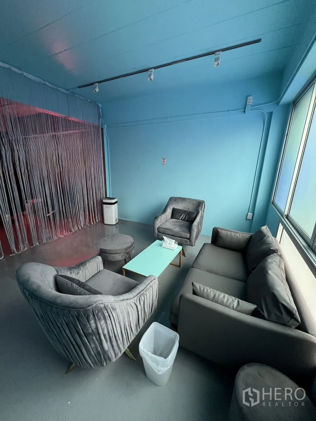 Shophouse for rent or sale in Watthana, Bangkok - Bright meeting lounge with gray sofas around a mint coffee table beside a large window.