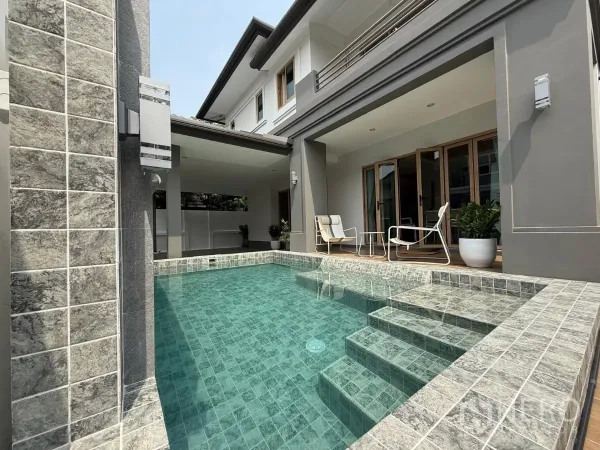 Detached House for sale in Suan Luang, Bangkok - Private swimming pool with tiled steps beside a covered terrace and folding glass doors of a renovated two‑storey house.