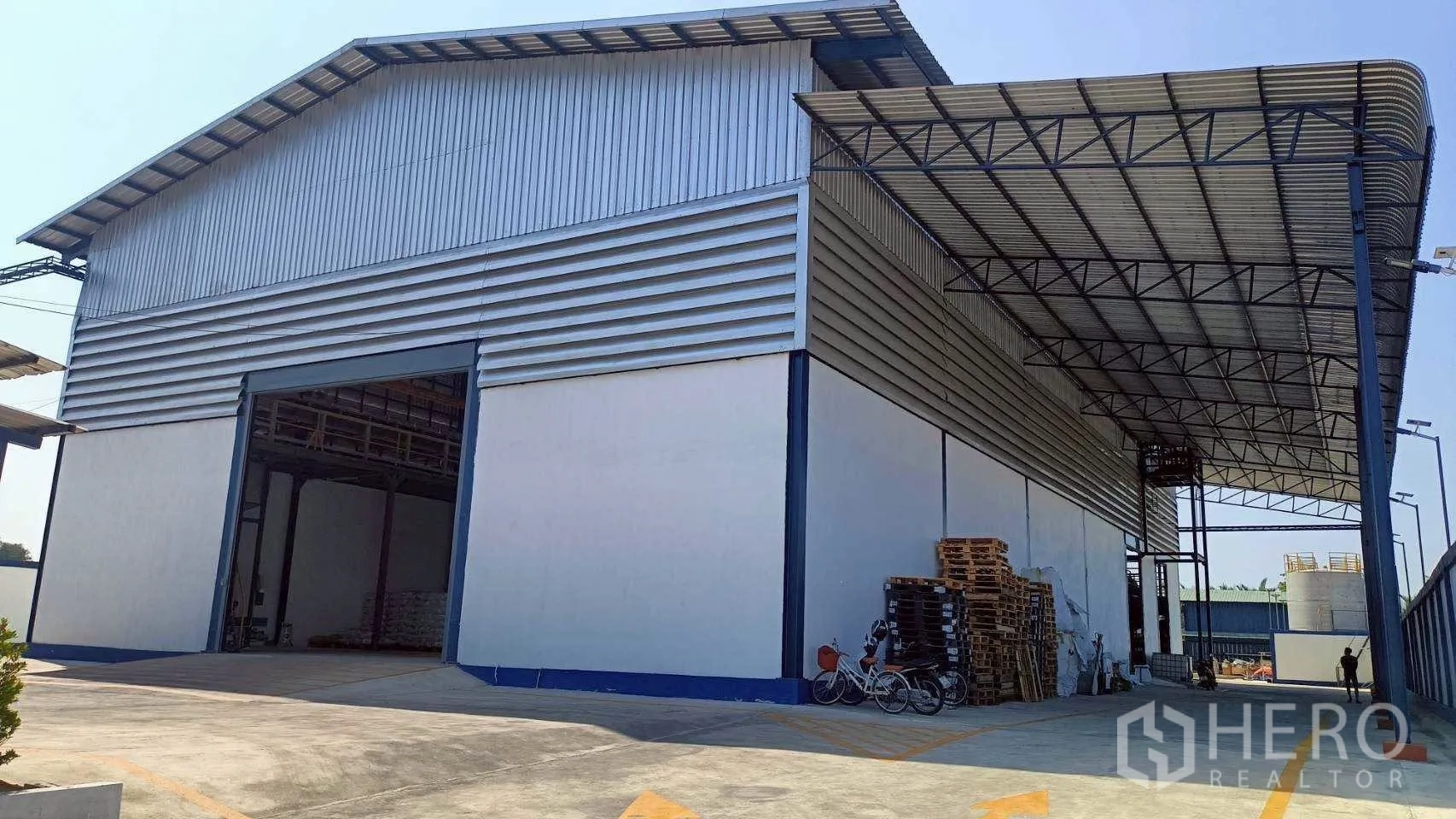 工厂 for rent or sale in Mueang Samut Sakhon, Samut Sakhon - 仓库旁带顶装卸区，配高卷帘门与堆放的托盘。