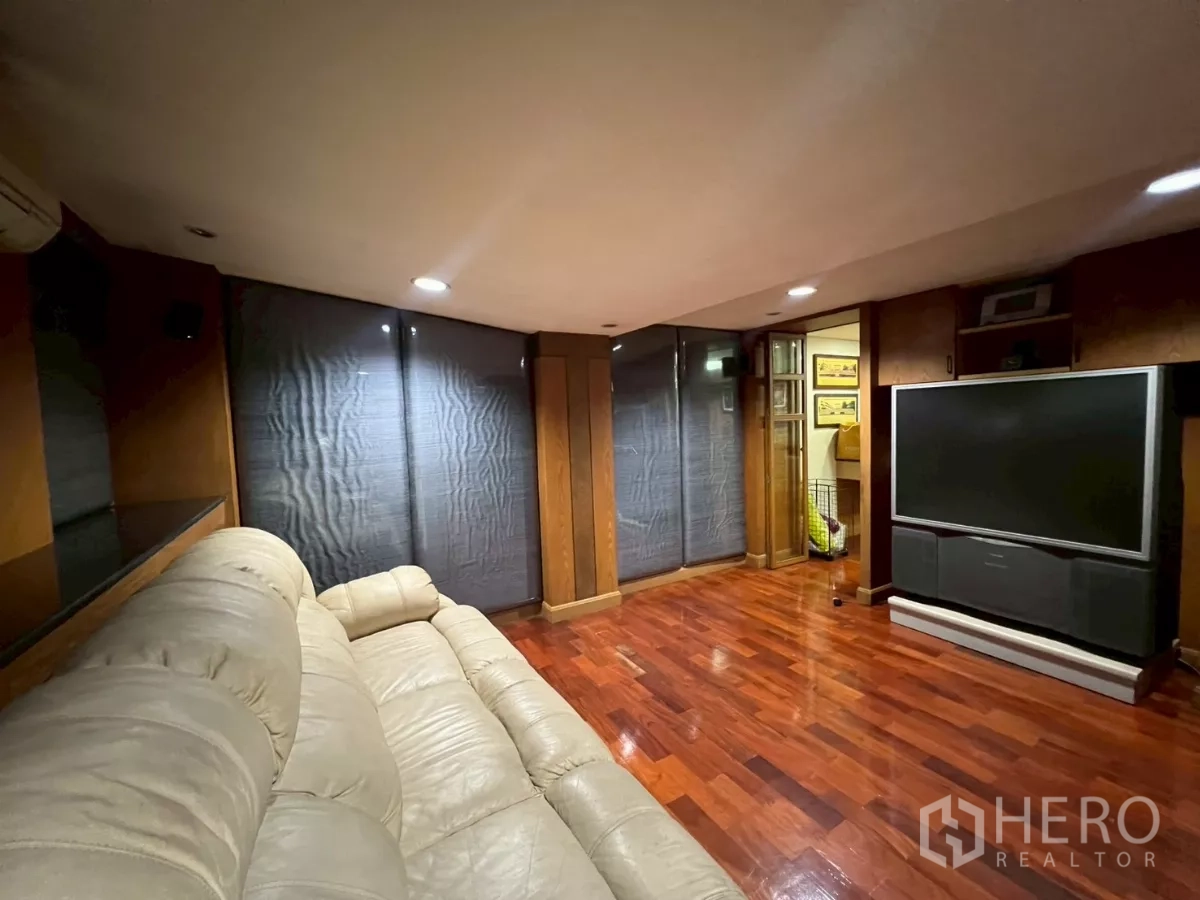 Shophouse for rent in Bang Rak, Bangkok - Media lounge with leather sofa, large TV and polished wooden flooring.