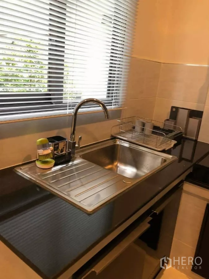 Detached House for rent or sale in Prawet, Bangkok - Kitchen sink beneath window with blinds and black stone countertop