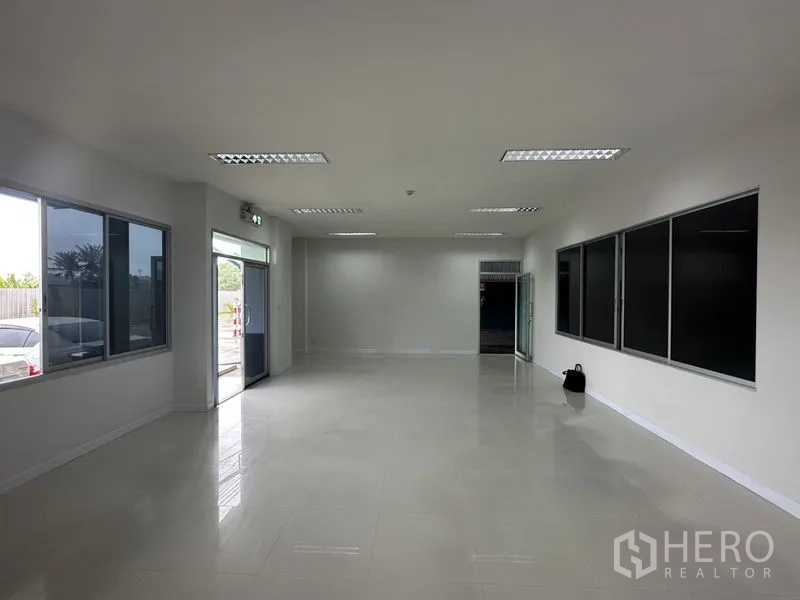 Factory for rent in Bang Phli, Samut Prakan - Bright ground-floor office with large windows, tiled flooring and a glass entrance door.