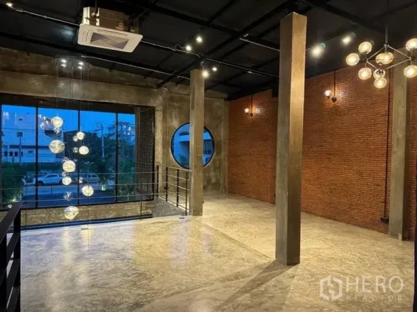 Standalone for rent in Sathon, Bangkok - Double-height space with hanging globe pendant lights, large picture window, round window and metal staircase railing.