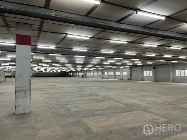 Factory for rent in Phra Samut Chedi, Samut Prakan - Spacious warehouse bay showing marked concrete flooring and structural columns.
