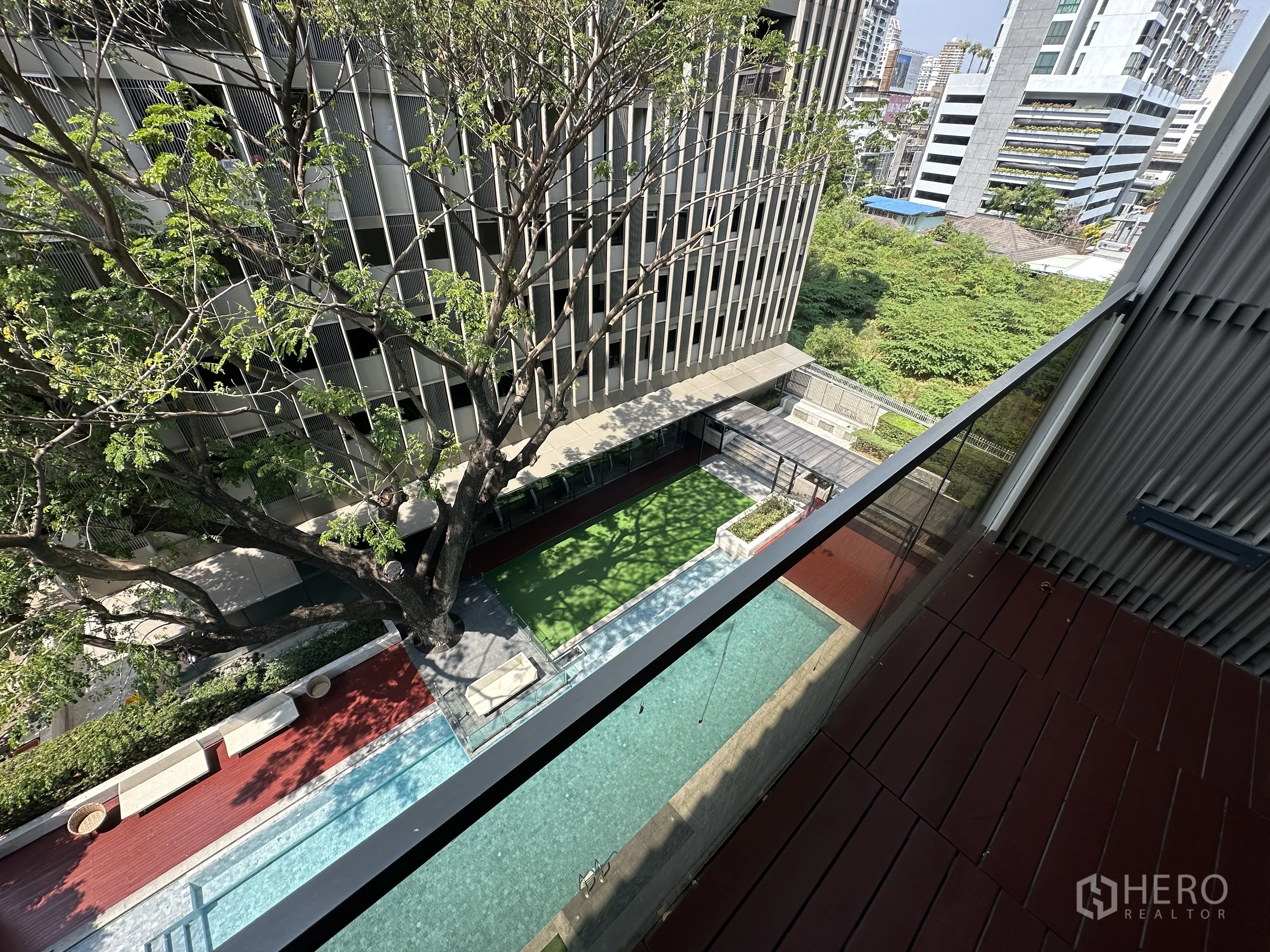 Condominium for rent in Khlong Toei, Bangkok - High-floor balcony view across landscaped courtyard and lap pool.