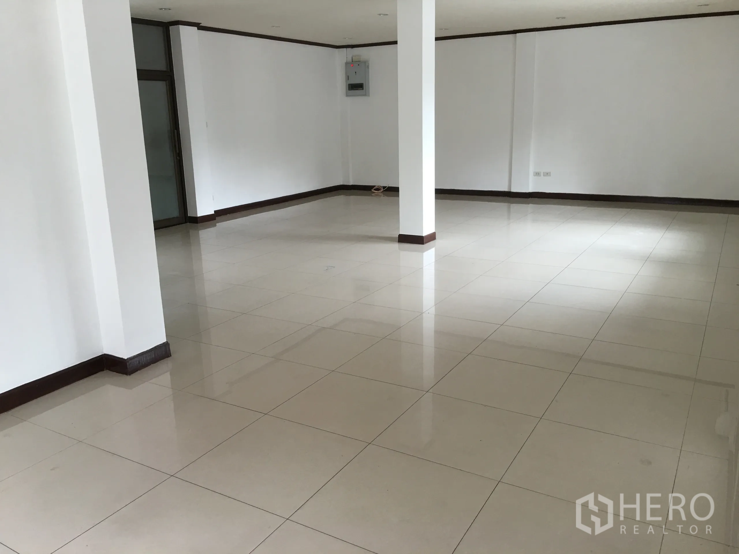 联排别墅 出租在Khlong Toei, Bangkok - 开放式客厅，白墙与光亮瓷砖地面，带结构立柱