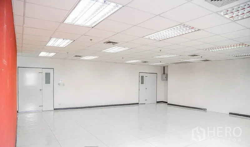 Office Space for rent in Bang Na, Bangkok - Open-plan office with white tiled floors, multiple doors, and a red wall.