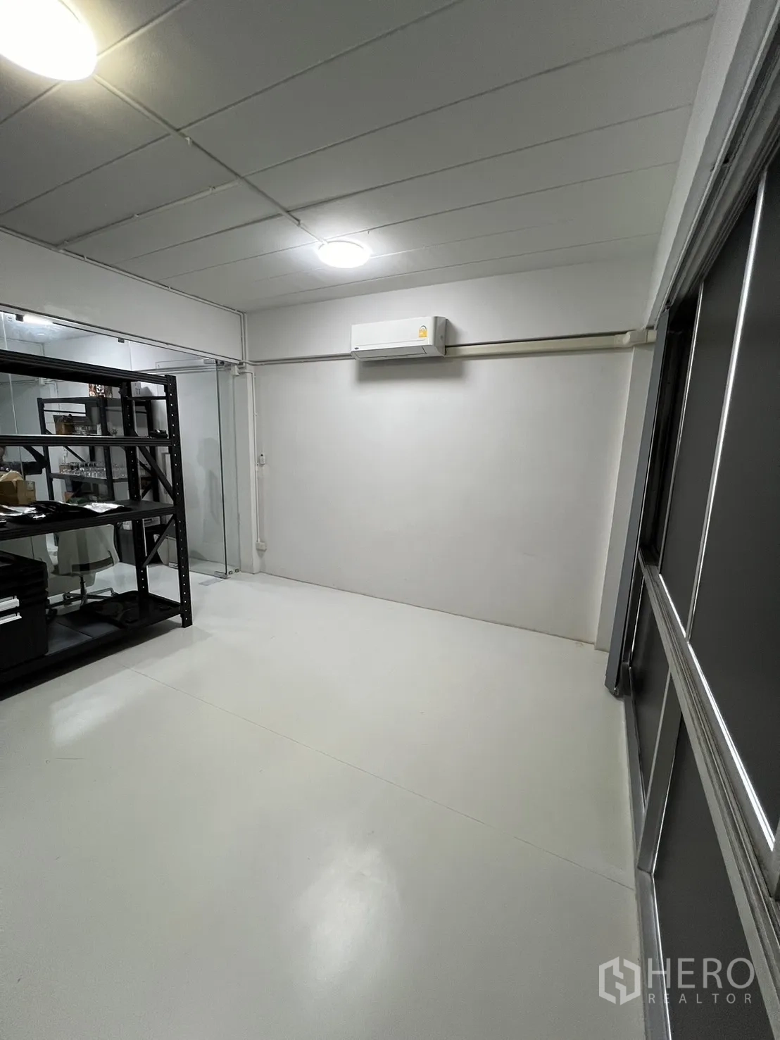 Shophouse for rent or sale in Watthana, Bangkok - Storage or back office with glass partition and shelving units.