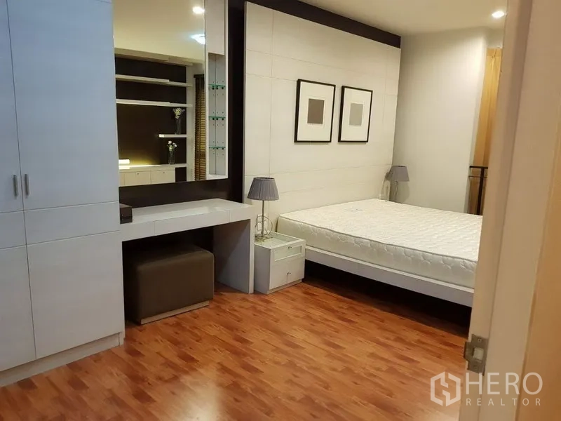 Townhouse for rent in Phra Khanong, Bangkok - Bedroom with built-in wardrobe, dressing counter and queen bed on wood flooring.