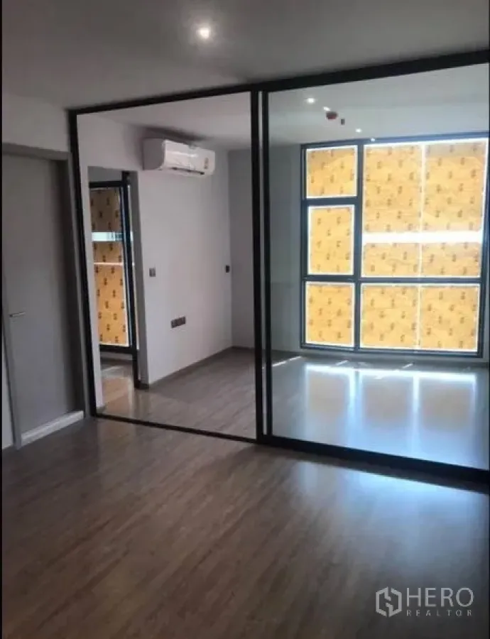 Condominium for sale in Khlong Toei, Bangkok - Bedroom zone behind black-framed glass wall with large window and air conditioner in a modern condo.
