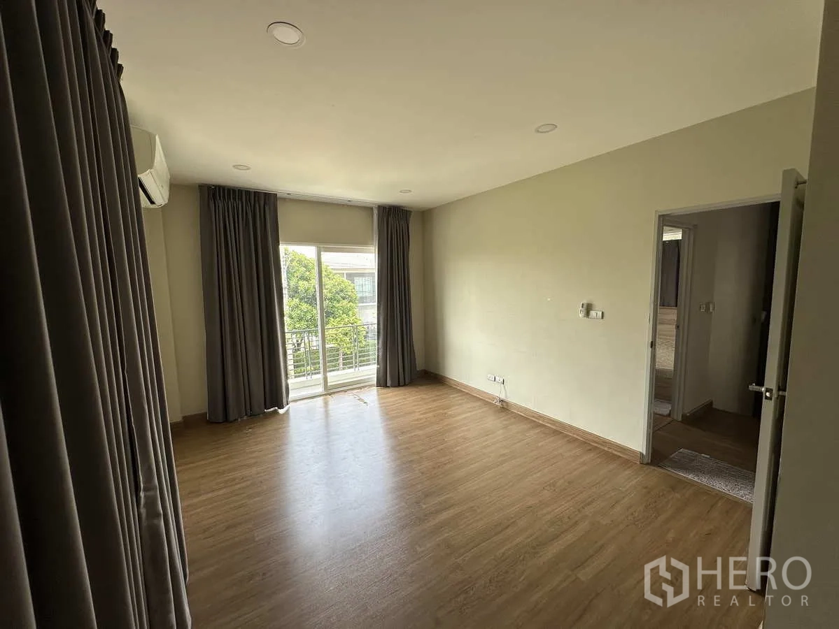 Detached House for rent in Khlong Luang, Pathum Thani - Secondary bedroom with AC, curtains and laminate wood flooring.