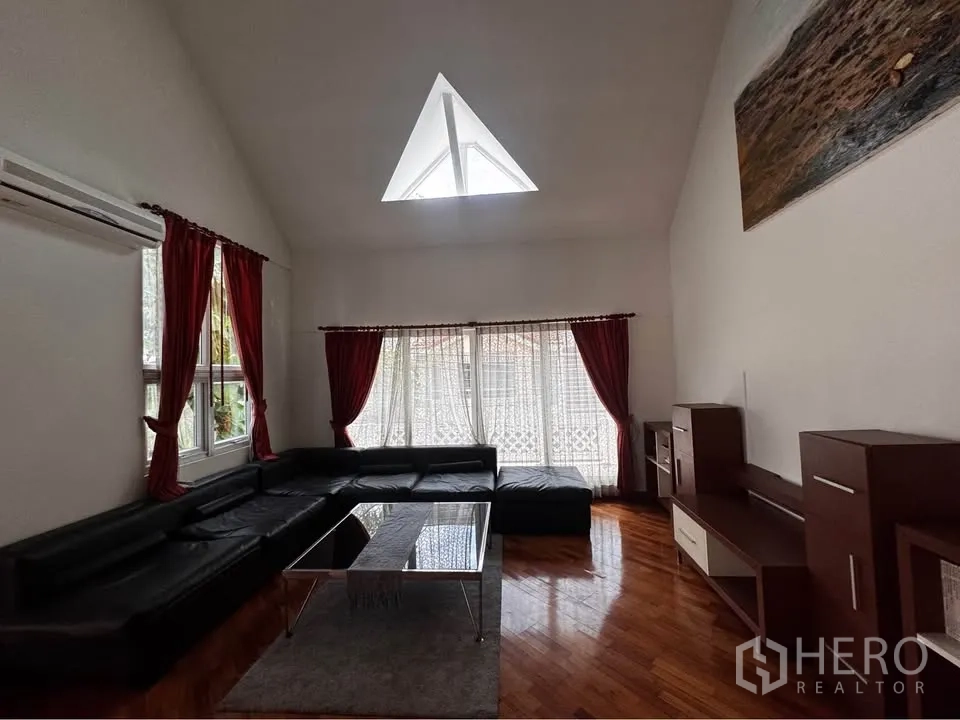 Townhouse for rent in Huai Khwang, Bangkok - Upper lounge with sectional sofa, wood floors and a triangular skylight.
