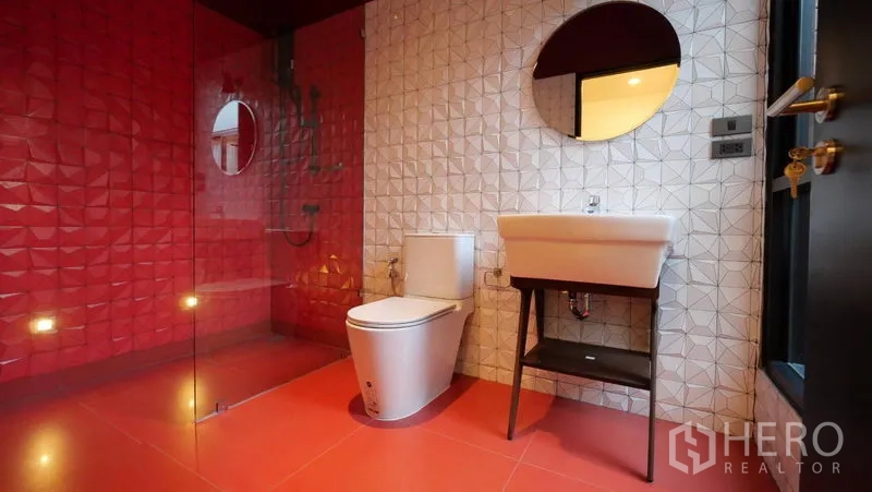 Townhouse for rent in Khlong Toei, Bangkok - Designer bathroom with bold red and white textured tiles, glass shower, and round mirror.