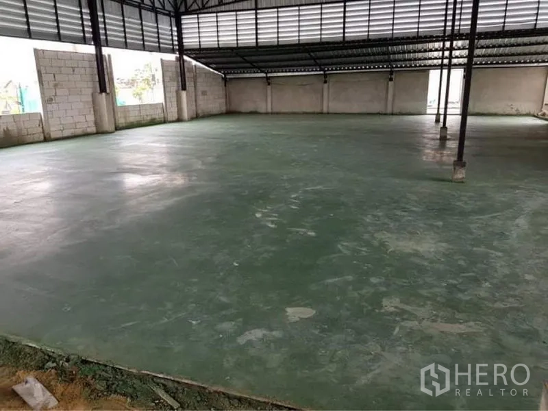 Warehouse for sale in Lam Luk Ka, Pathum Thani - Spacious warehouse interior with green epoxy concrete floor and steel truss roof.
