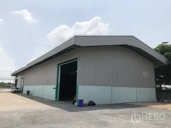 Warehouse for rent in Bang Bua Thong, Nonthaburi - Corner view of single-storey warehouse with high gable roof and large sliding door.