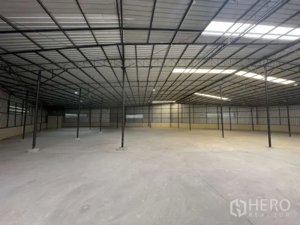 货栈 出租在Pak Kret, Nonthaburi - 宽敞开阔的仓库内部，钢结构屋架，天窗采光与混凝土地面。