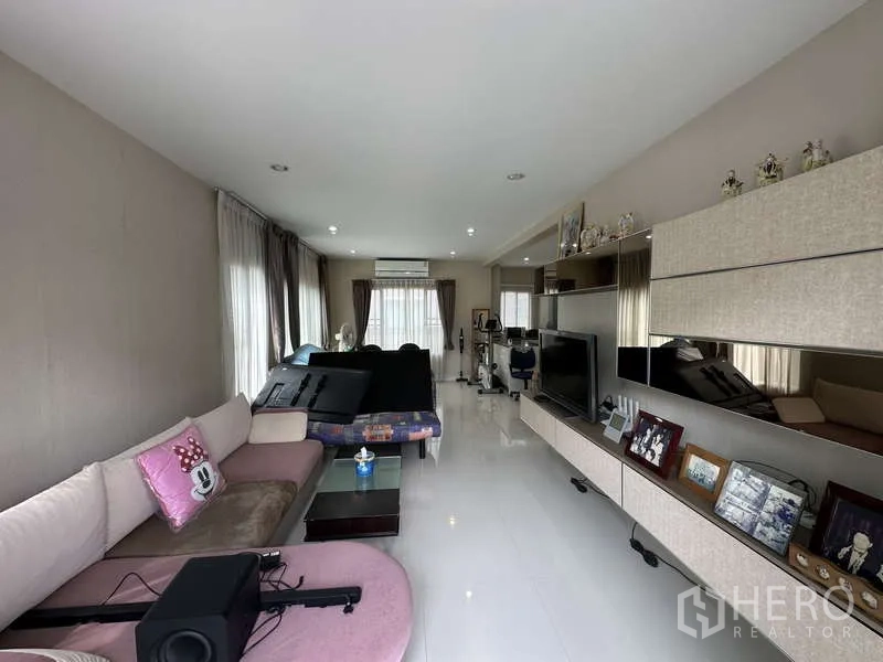 独立式住宅 出售在Sai Mai, Bangkok - 采光良好的长形客厅，沙发组与电视墙。