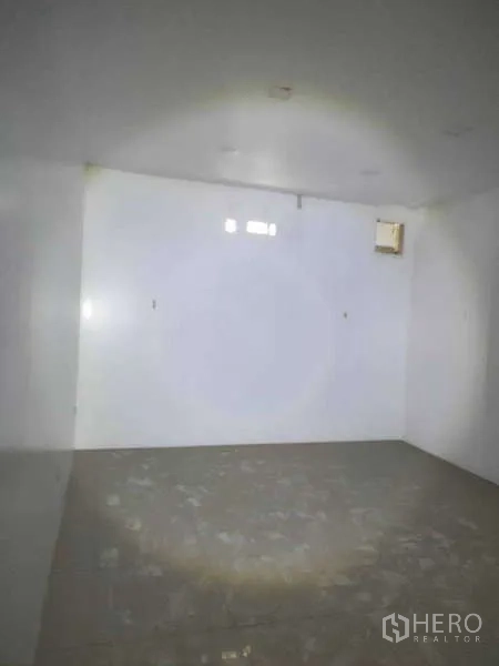 Shophouse for sale in Phra Khanong, Bangkok - Empty white storage room with small vents and a tiled floor.