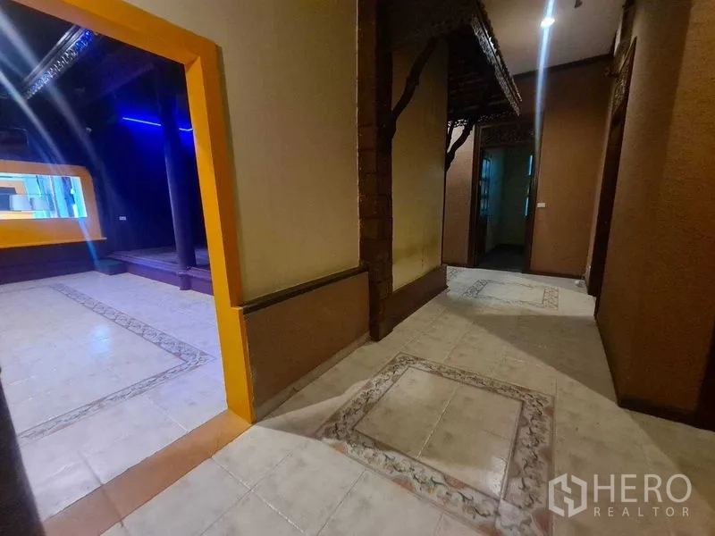 Retail Space for rent in Watthana, Bangkok - Corridor with patterned tiles opening to a purple retail room with a raised platform.