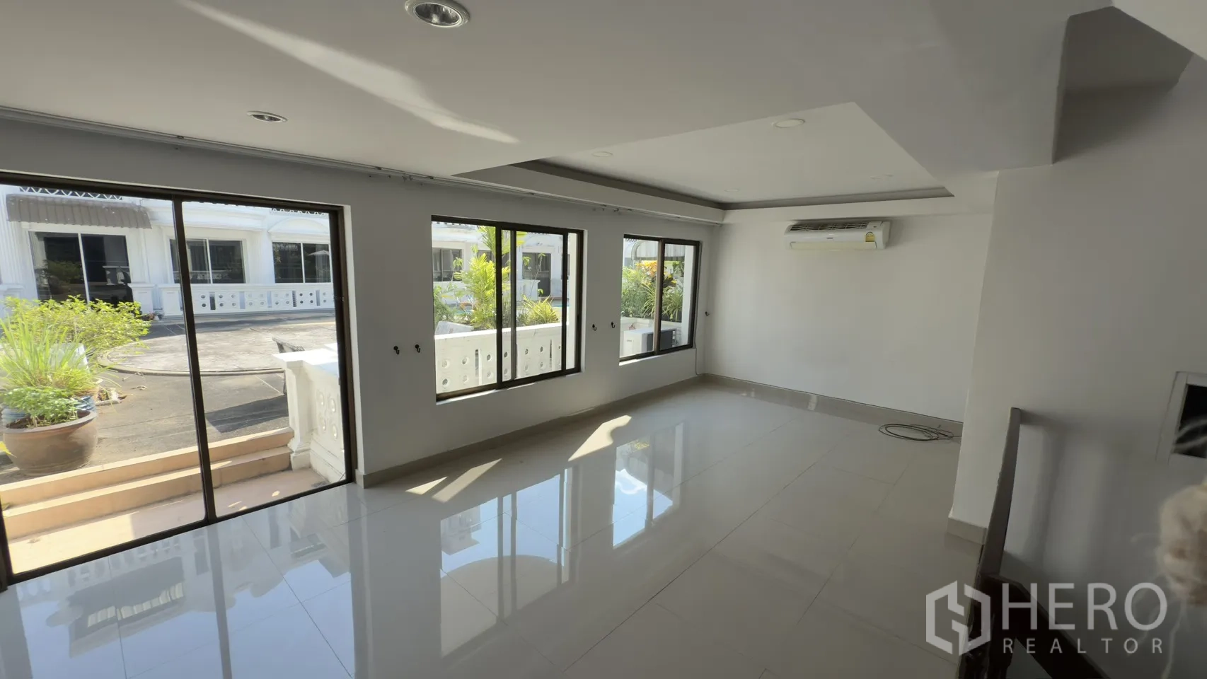 Townhouse for rent in Watthana, Bangkok - Sunlit living area with several sliding windows opening to a balcony with planters.
