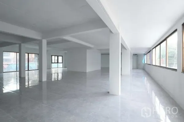 Retail Space for rent in Pathum Wan, Bangkok - Open-plan interior with structural columns and wide windows on two sides under a bright white ceiling.