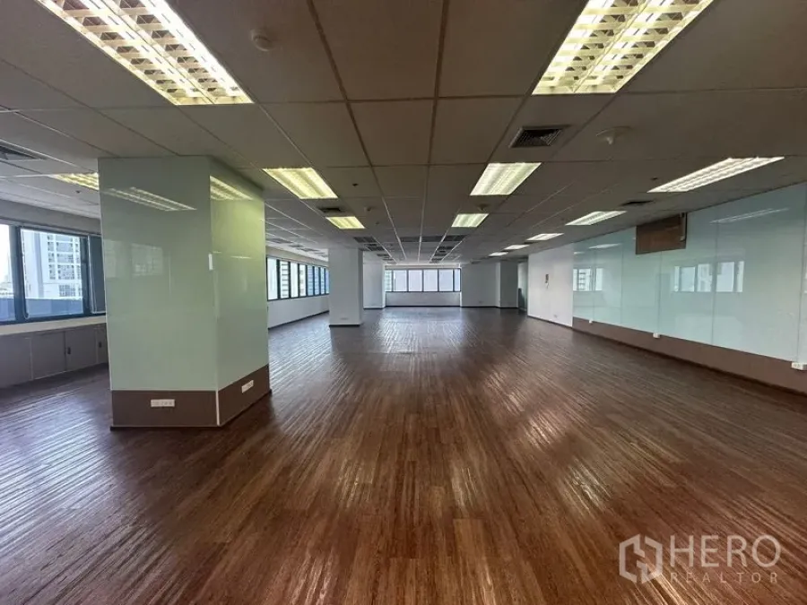 Office Space for rent in Bang Rak, Bangkok - Wide open-plan office with glass-wrapped columns and ceiling lights.
