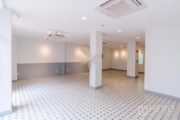 带办公室的家 出租在Khlong Toei, Bangkok - 宽敞的白色室内空间，画廊式灯光、瓷砖地面与承重立柱，适合展厅或办公。