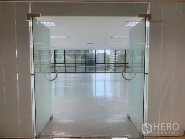 Office Space for rent in Bang Rak, Bangkok - Glass double doors open to a bright open‑plan office with glossy floors and a wide wall of windows.