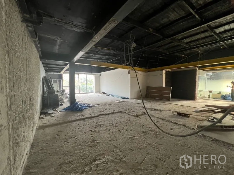 Retail Space for rent in Watthana, Bangkok - Spacious bare retail floor with exposed ceiling and hanging wiring, window at far end.