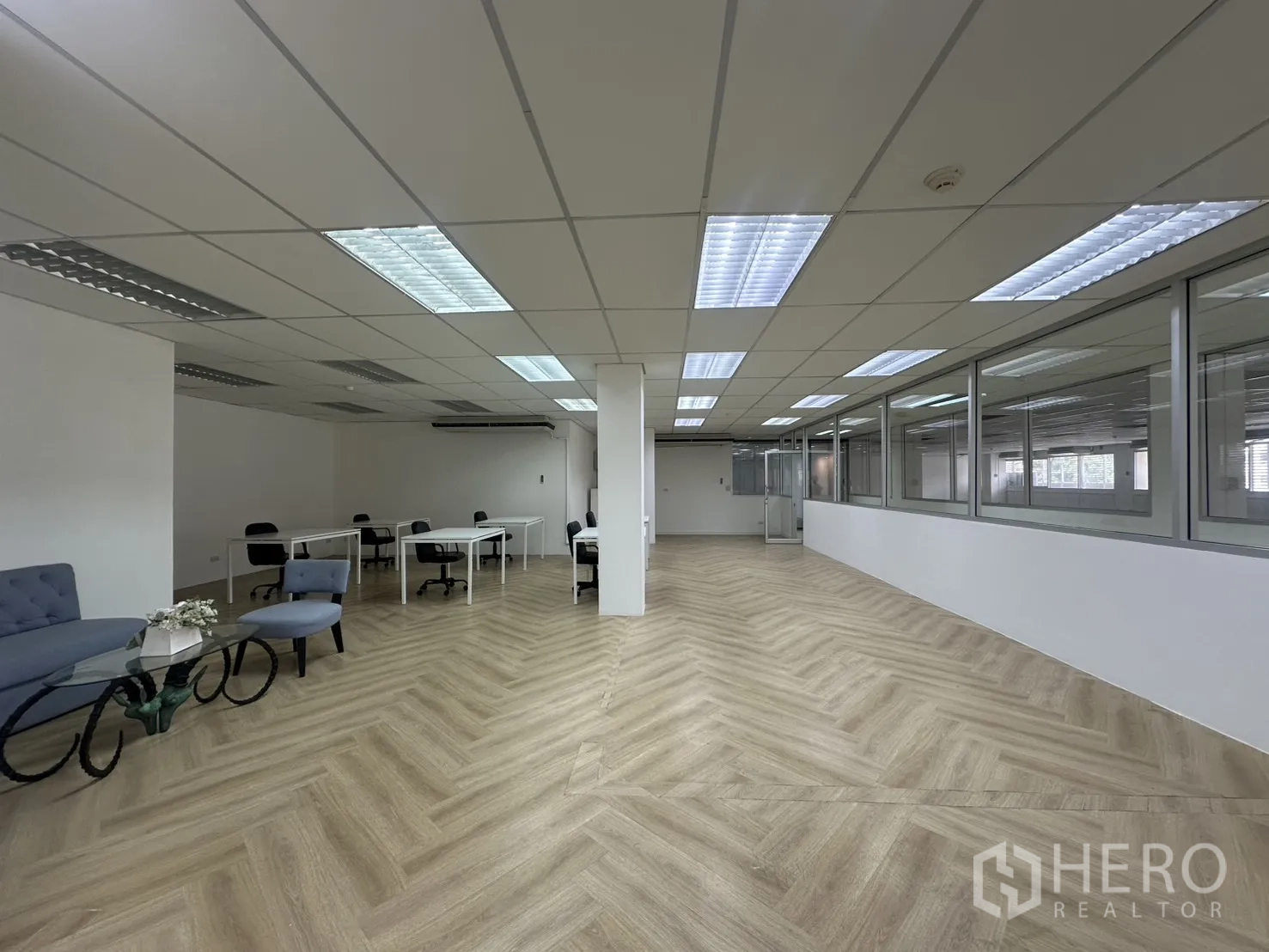 Office Space for rent in Pathum Wan, Bangkok - Spacious office showing desks, lounge seating, and glass partitions under a grid ceiling with bright lighting.