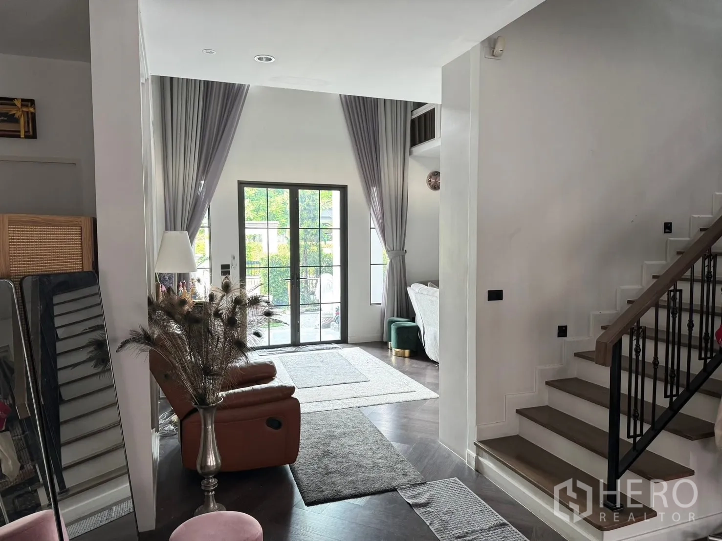 Detached House for sale in Mueang Pathum Thani, Pathum Thani - Open living space with staircase, tall curtains and French doors to the garden.