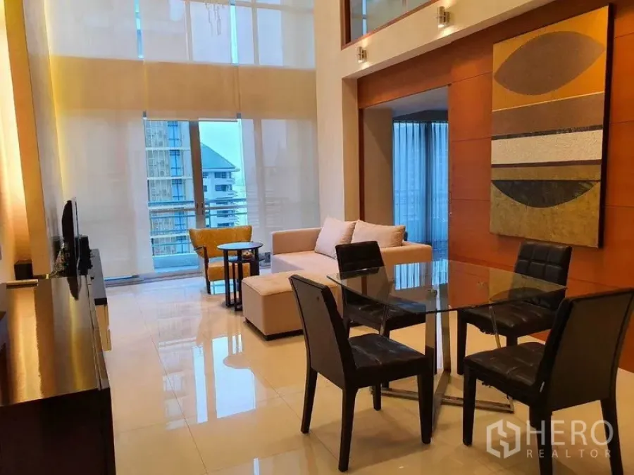 Condominium for rent in Pathum Wan, Bangkok - Double-height living and dining room with glass table, sofa and balcony access.