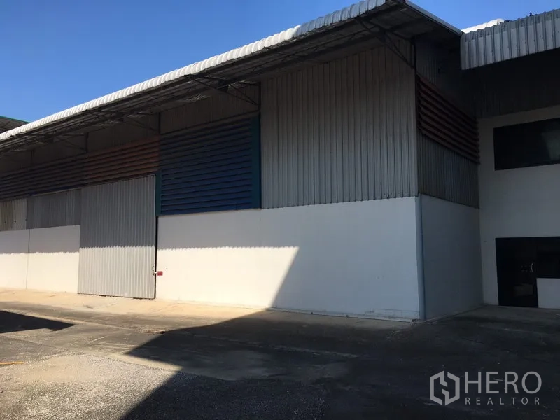 Warehouse for rent in Saphan Sung, Bangkok - Side elevation of warehouse with metal louver panels and covered loading area.