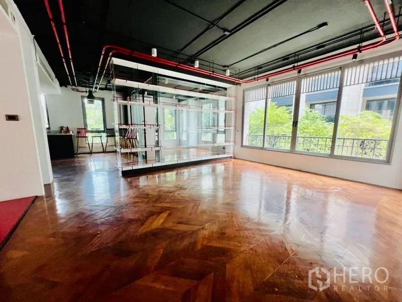 Office Space for rent in Khlong Toei, Bangkok - Spacious office area with mirrored glass shelving, exposed red pipes and wide windows.
