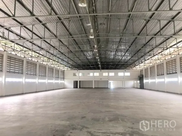 Factory for rent or sale in Bang Pa-in, Phra Nakhon Si Ayutthaya - Vast production hall with high steel truss roof, louvered vents and concrete floor.