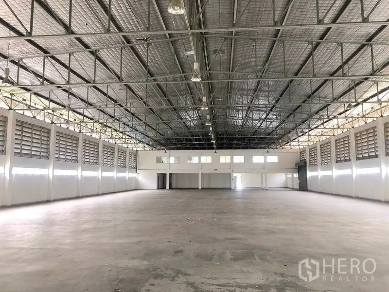 Factory for rent or sale in Bang Pa-in, Phra Nakhon Si Ayutthaya - Vast production hall with high steel truss roof, louvered vents and concrete floor.