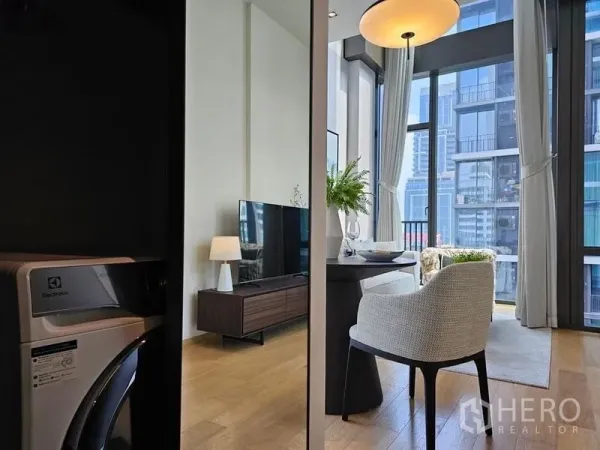 Condominium for rent - View of the living area with TV console and dining set beside floor-to-ceiling glass, washer in foreground.