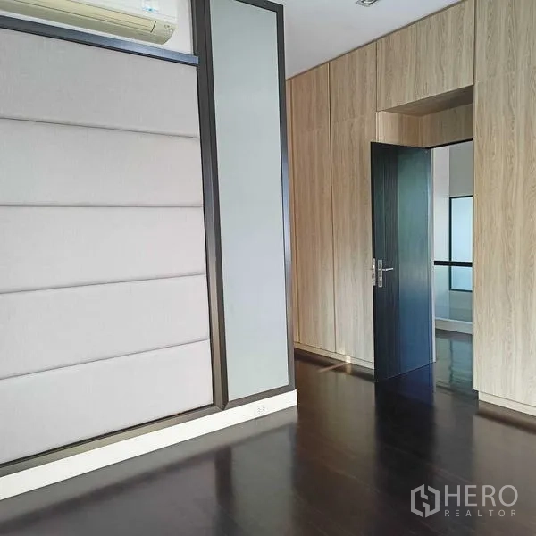 Detached House for rent or sale in Mueang Nonthaburi, Nonthaburi - Upper floor room with padded accent wall and dark timber flooring.
