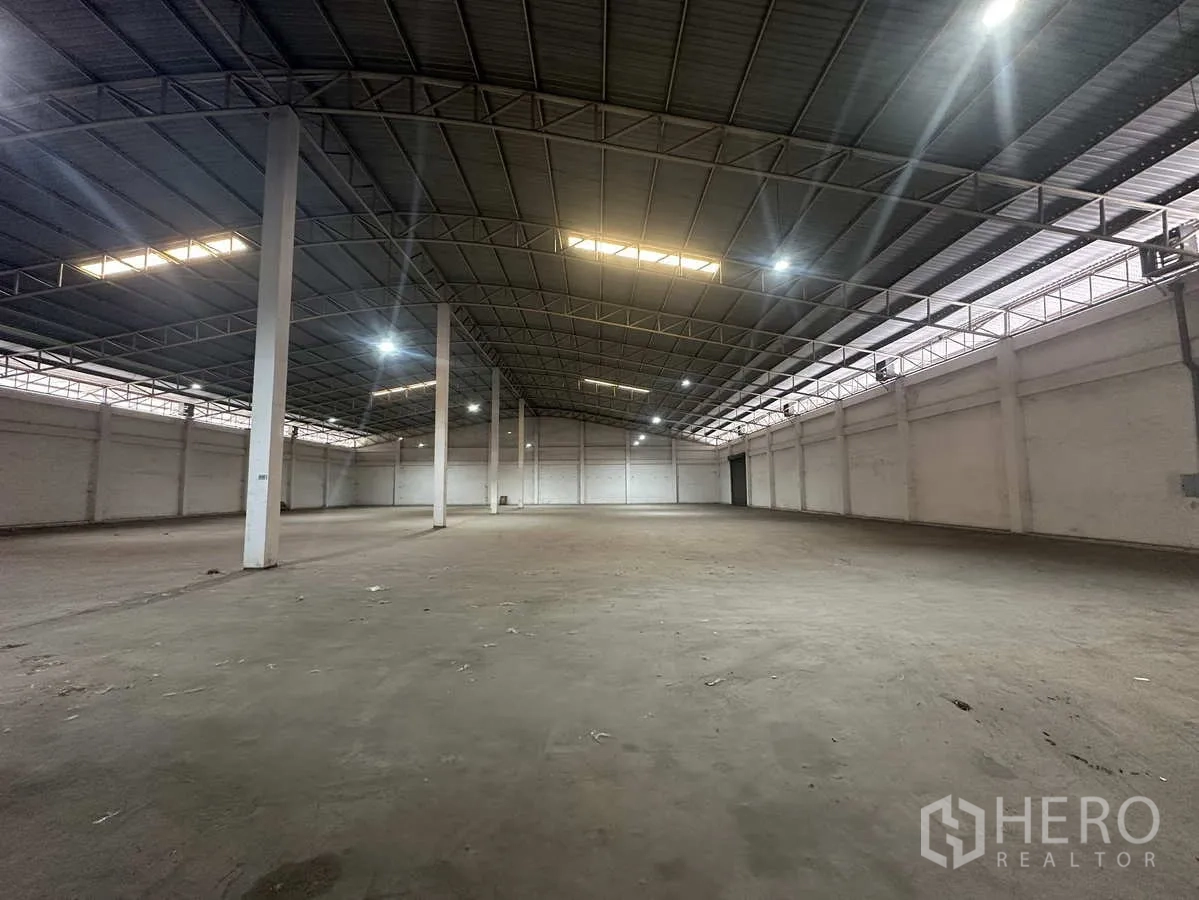 Warehouse for rent in Phra Nakhon Si Ayutthaya - Open storage hall featuring steel trusses, skylights and LED lighting along the roofline.