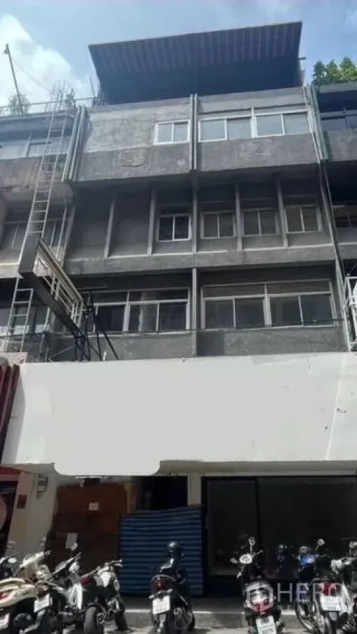 Shophouse for rent in Bang Rak, Bangkok - Four-storey shophouse facade in Silom, Bang Rak with glass storefront and motorbikes parked outside.