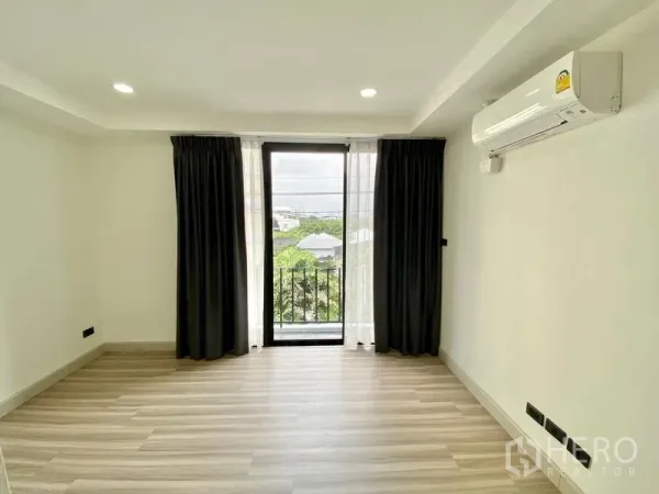 Home Office for rent or sale in Bang Na, Bangkok - Bedroom with floor-to-ceiling window, balcony view, blackout curtains and wall-mounted air conditioner.